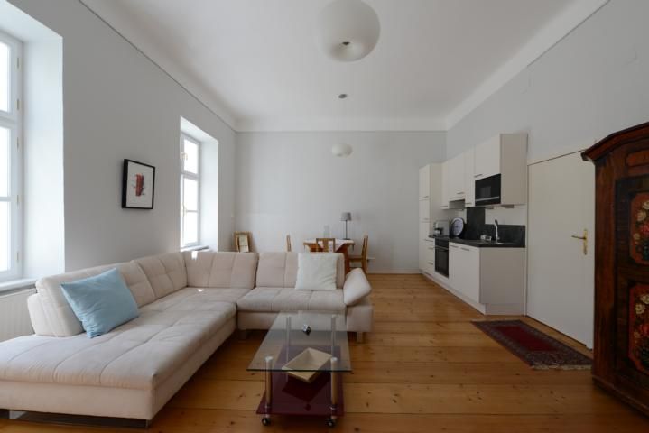 Bright living room with corner sofa, glass table, dining table and kitchenette.