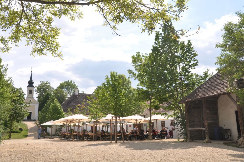 A village inn in the museum village with parasols and a church in the background.