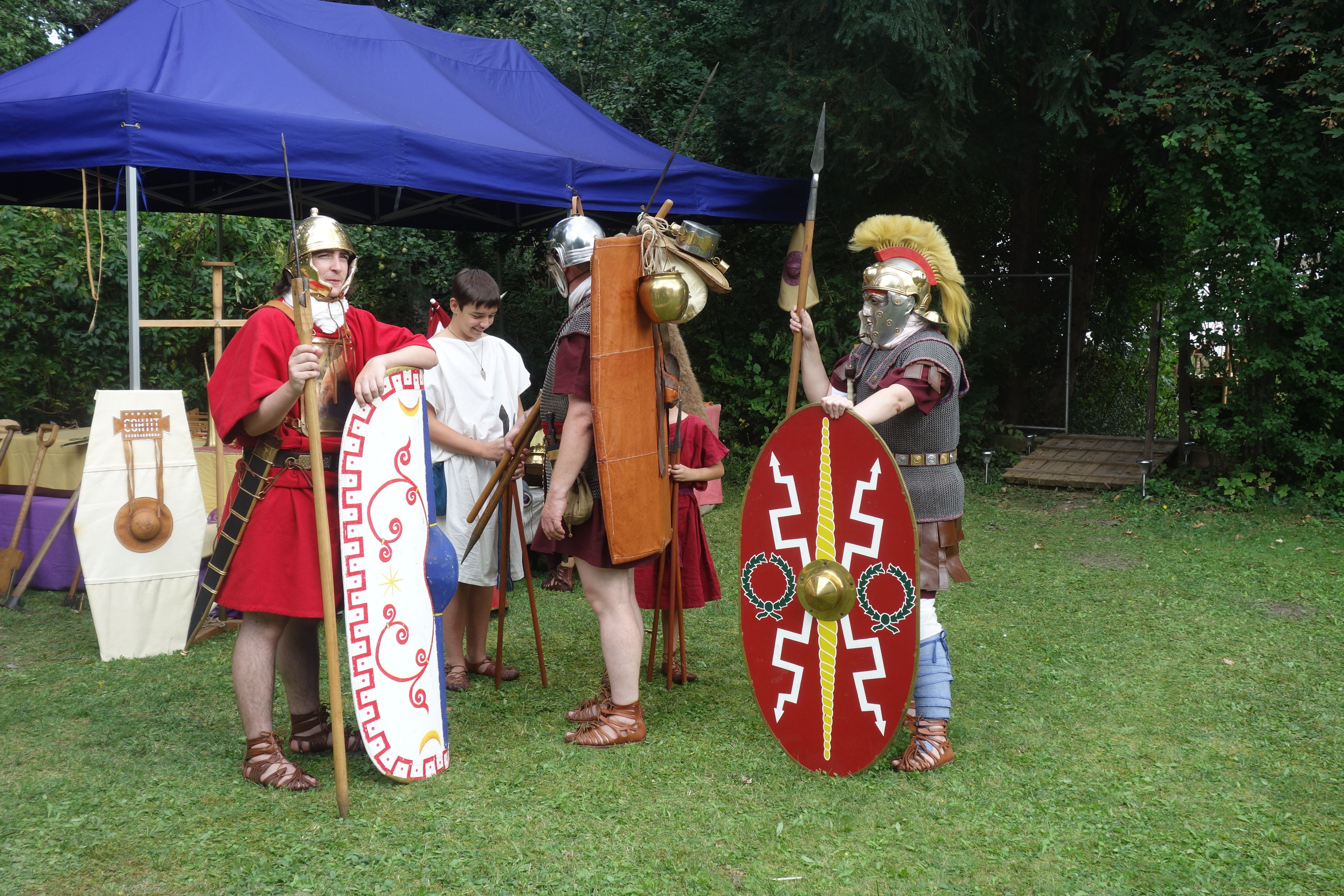 People in Roman armor during a historical re-enactment outdoors.