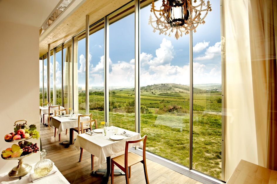 Interior view of a restaurant with large windows and a view of a green landscape.