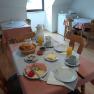 A laid breakfast table with bread rolls, cold cuts, cheese and orange juice in a cozy room.
