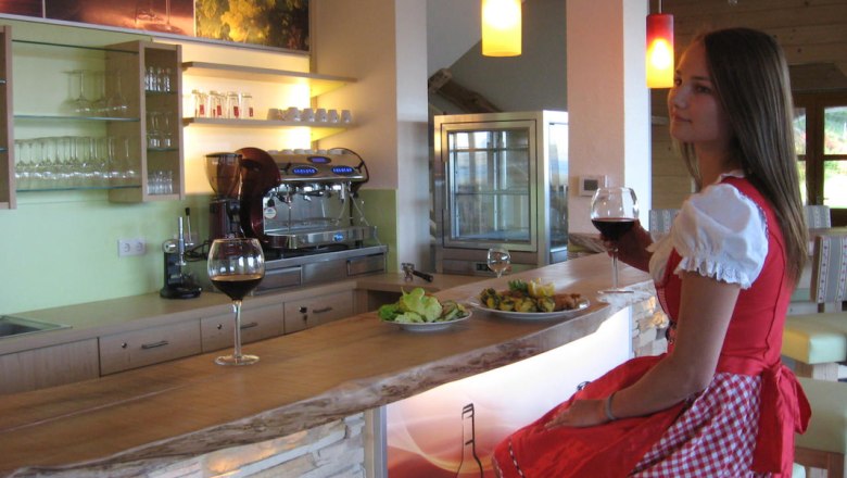 Woman in traditional dress sitting at a bar with a glass of red wine.