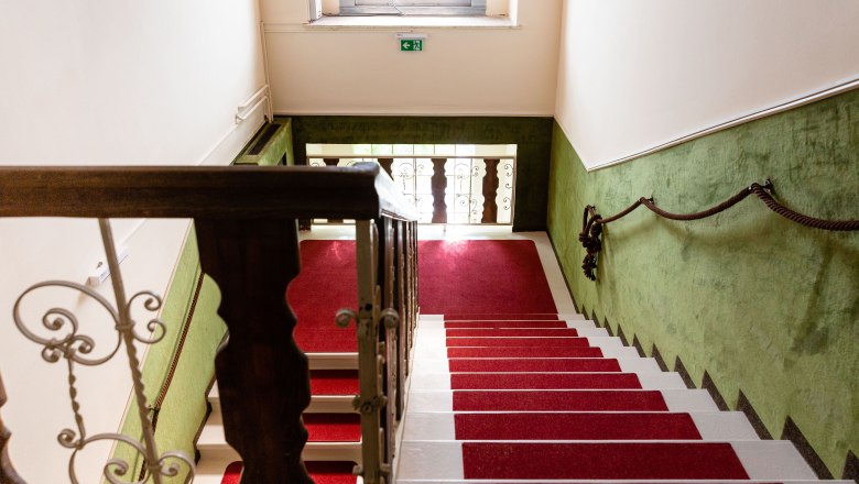 Staircase with red carpet and green-painted walls.