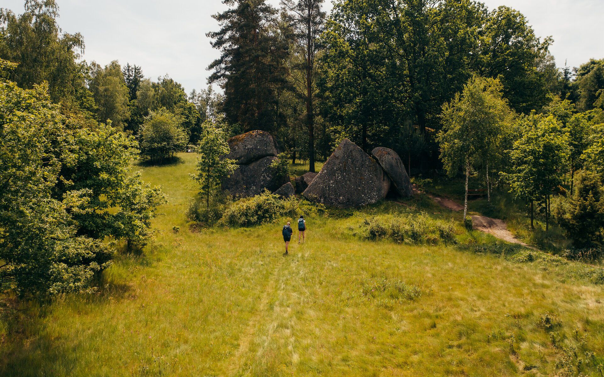 Two people walk towards the stone formations in the Blockheide