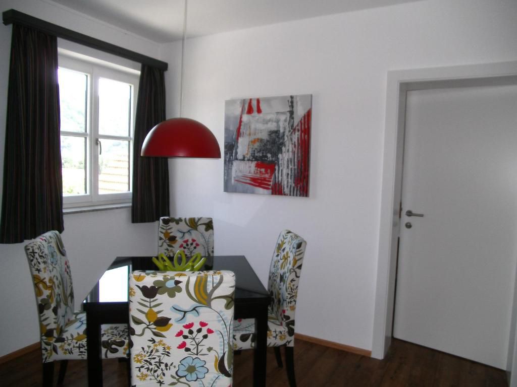 Dining area with floral patterned chairs, red hanging lamp and modern artwork on the wall.