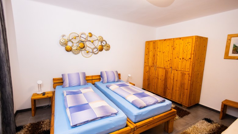 Bedroom with two single beds, wooden furniture and wall decoration.