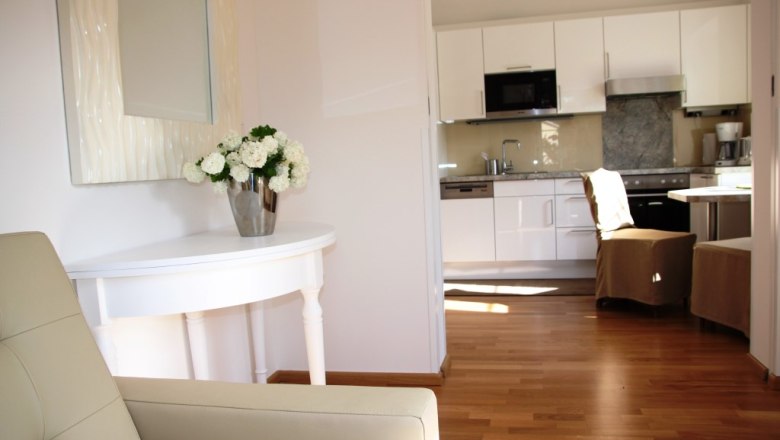 Old gatehouse, © © Elisabeth Hofer Interior view of a modern living area with kitchen and flowers on a table.