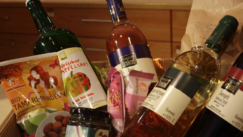 Gift basket with bottles of wine, apple juice and snacks.