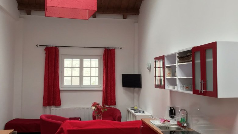Living and dining area in a loft with red furniture and wooden beamed ceiling.