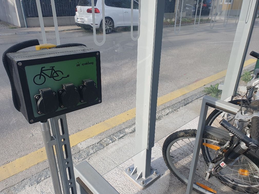 E-bike charging stations with sockets and bicycles next to it.