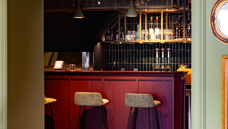 Elegant bar with red wooden furniture and high stools.