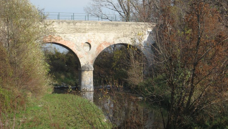 Old stone bridge over a small river, surrounded by trees in the fall.