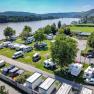 Aerial view of a campsite by the river with mobile homes and tents.