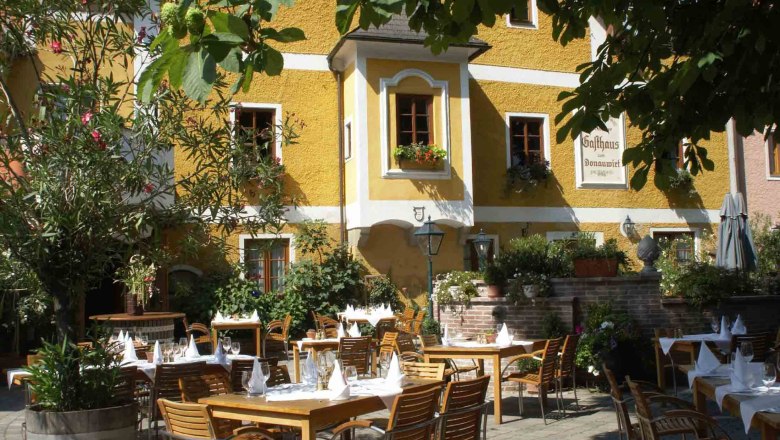 Terrace of an inn with laid tables and plants.