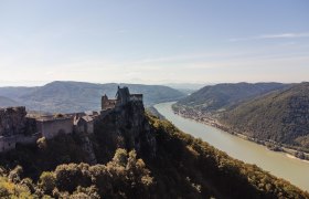 Aerial view of the Aggstein castle ruins with a view of the Danube and surrounding hills.