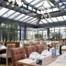 Interior view of a modern restaurant with glass roof and covered tables.