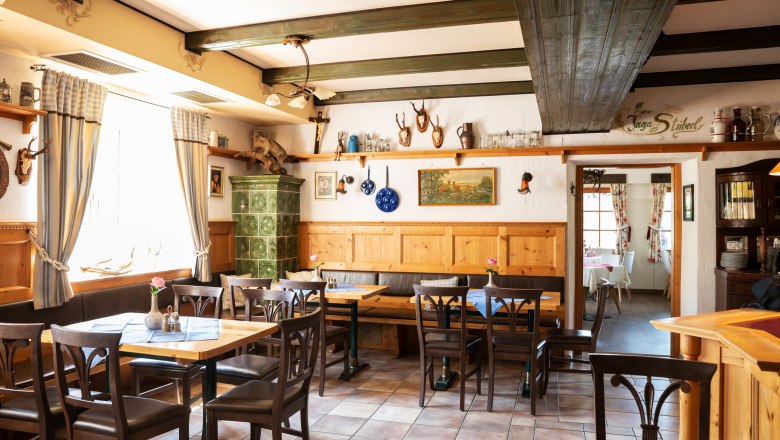 Cozy parlor with wooden furniture, tiled stove and hunting trophies on the walls.
