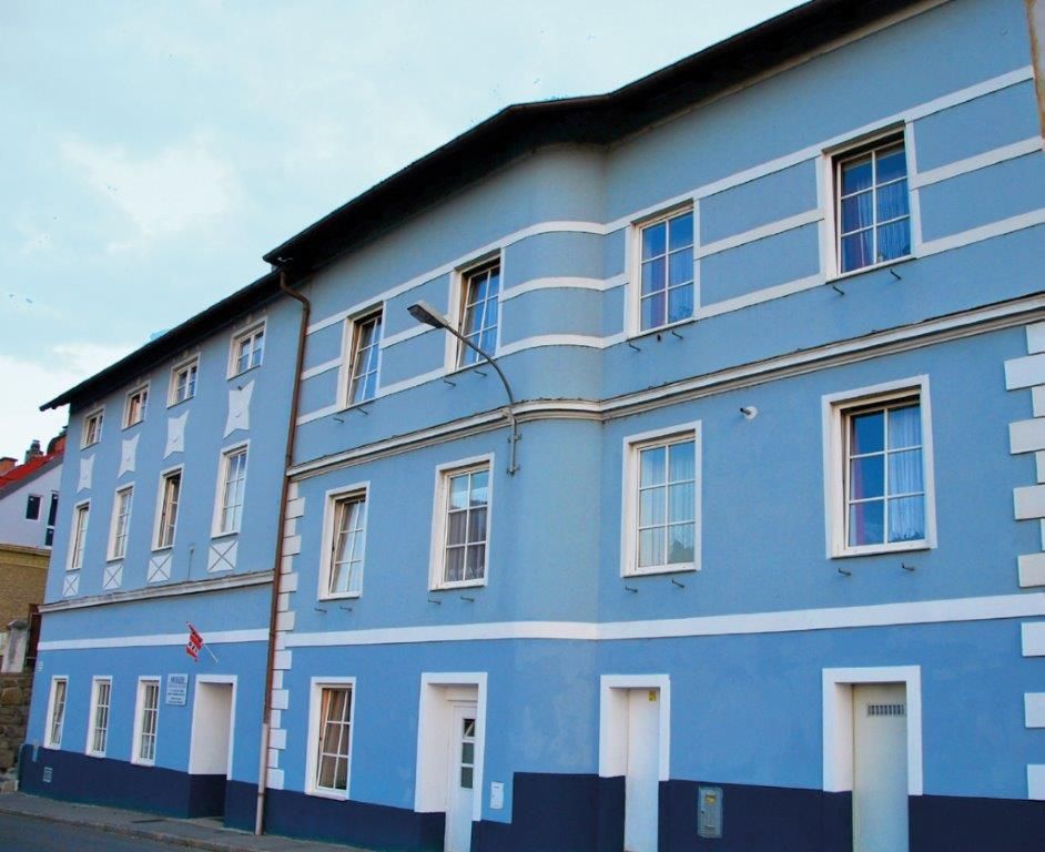 Blue façade of a multi-storey building with white window frames and doors.