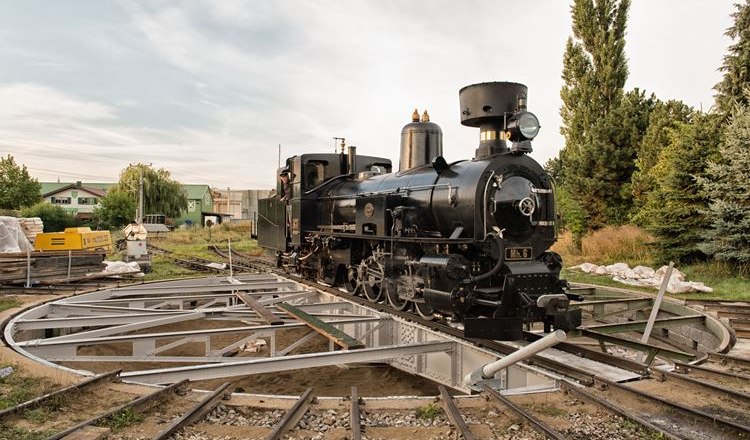 A black steam locomotive on a turntable outside.