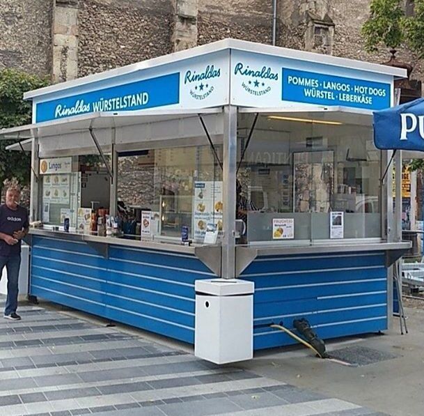 A blue snack stand called Rinalda's sausage stand with offers such as chips and hot dogs.