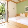Bright room with double bed, green-painted wall and balcony with mountain view.