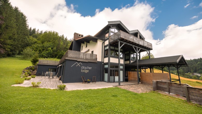 Ötscher Lodge, © Niederösterreich Werbung / Maximilian Pawlikowsky Ötscher Lodge in a green, wooded setting with a blue sky.