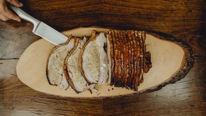 Sliced roast pork on a wooden board.