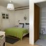 Comfortable double room with green bedspread, small desk and adjoining bathroom with shower.