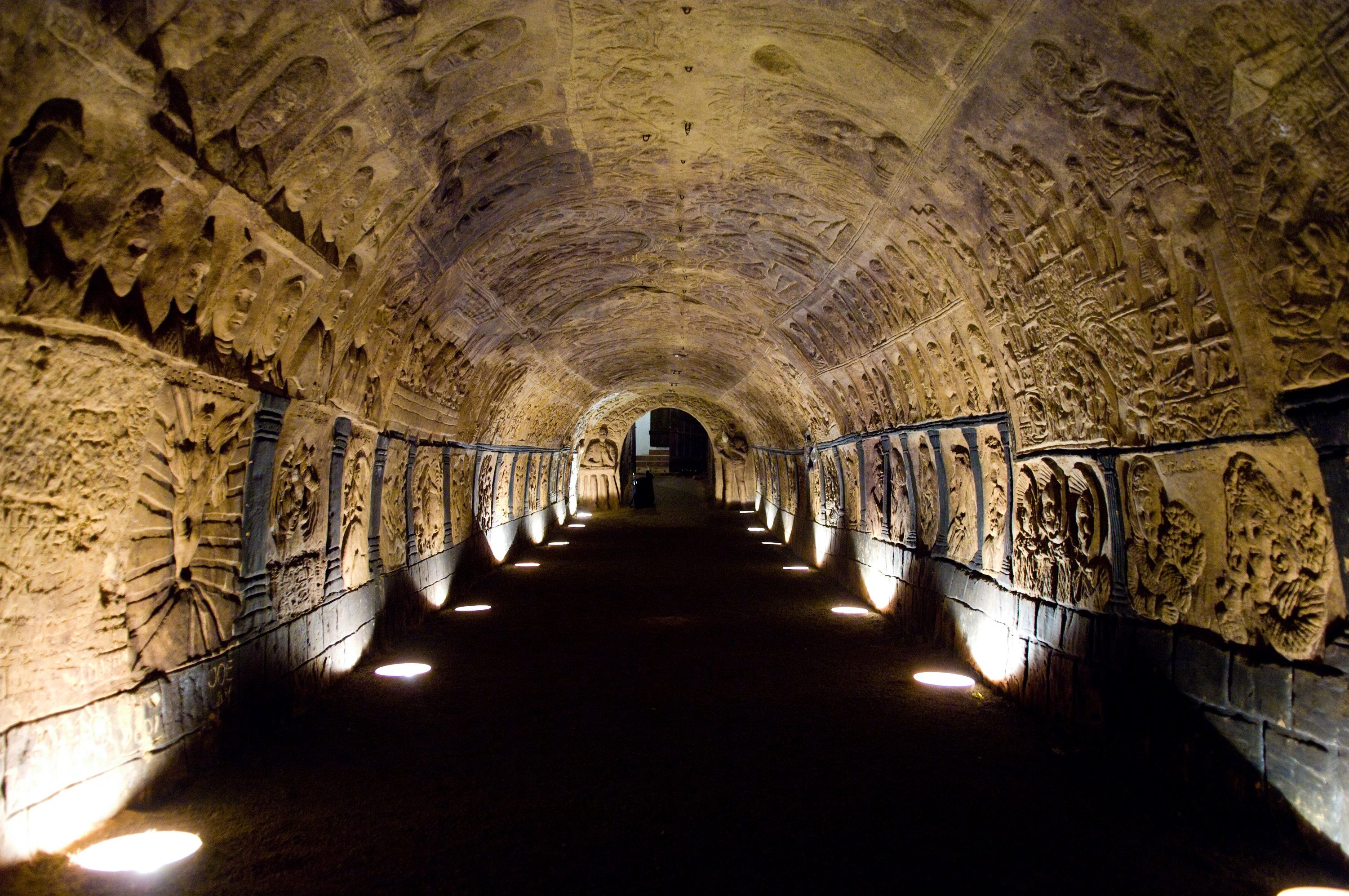 An illuminated tunnel with artistically carved walls and ceilings.