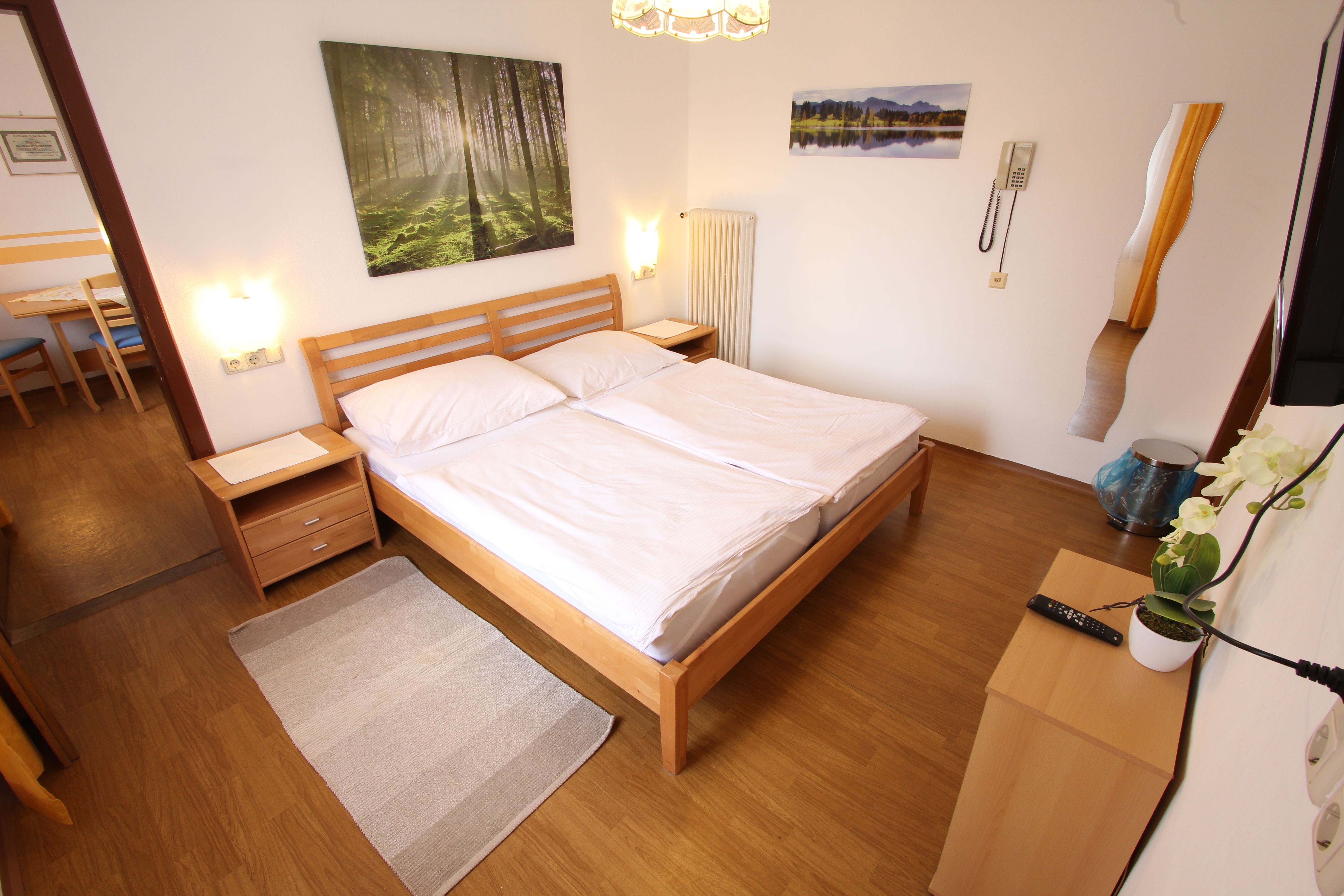 Bright bedroom with double bed, wooden furniture and pictures of nature on the wall.