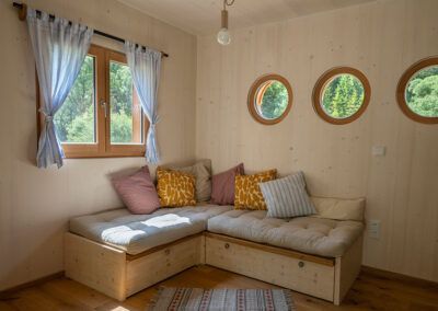 Cozy sitting area in a wooden modular house with round windows.