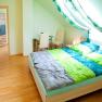 Bright bedroom with sloping ceiling, double bed, desk and chair.
