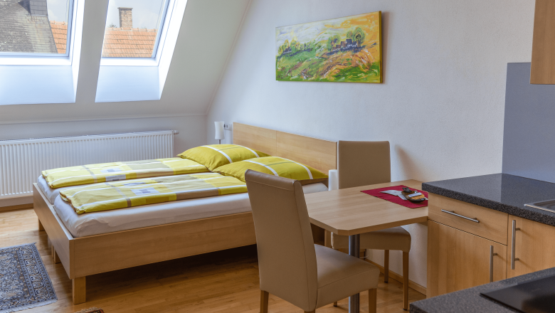 Double room with kitchenette, bed, table and chairs.