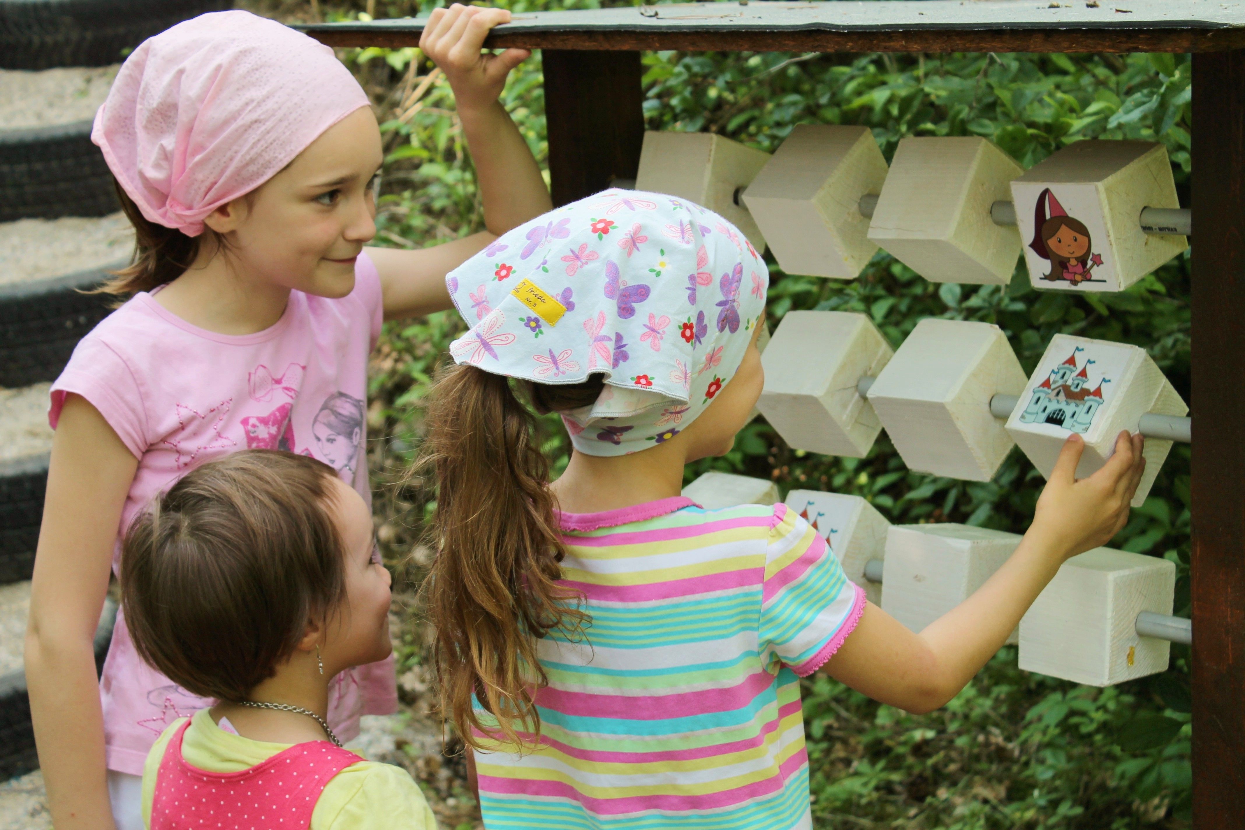 Three children playing on a piece of wooden outdoor play equipment.