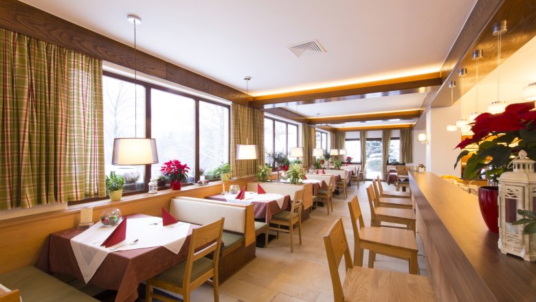 Interior view of a cozy restaurant with wooden furniture and large windows.