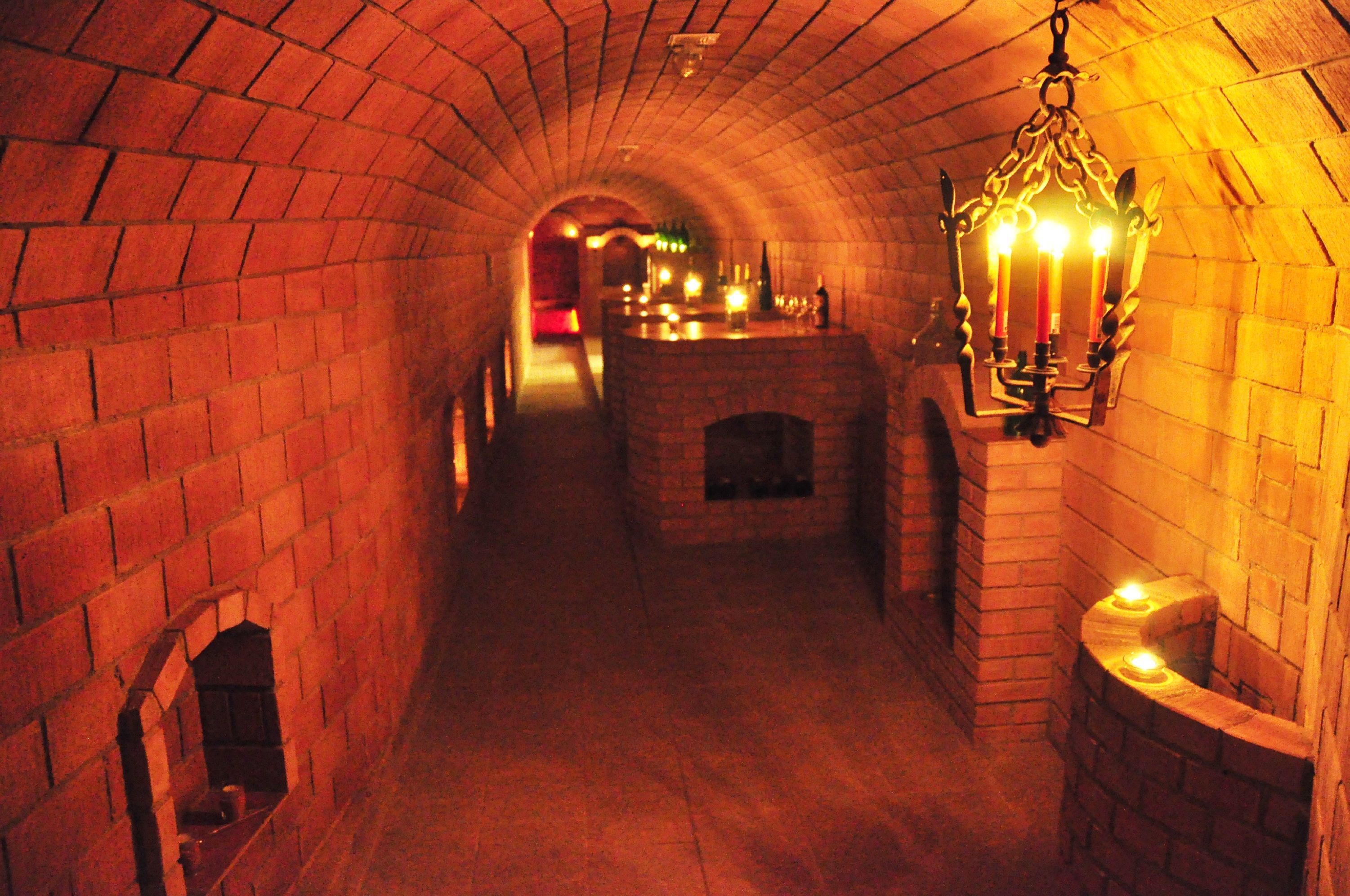 An illuminated wine cellar with brick walls and candlelight.