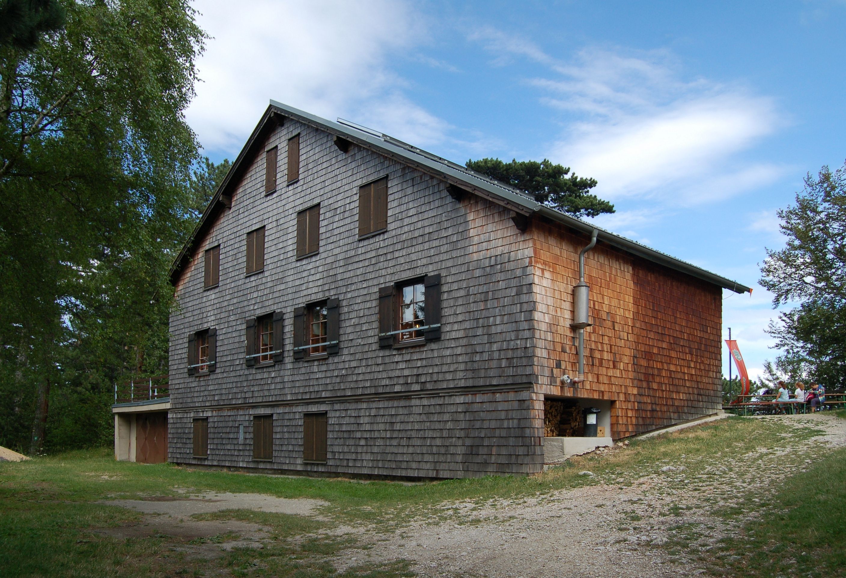 Neunkirchen house on the Flatzer Wand with wooden facade and blue sky.