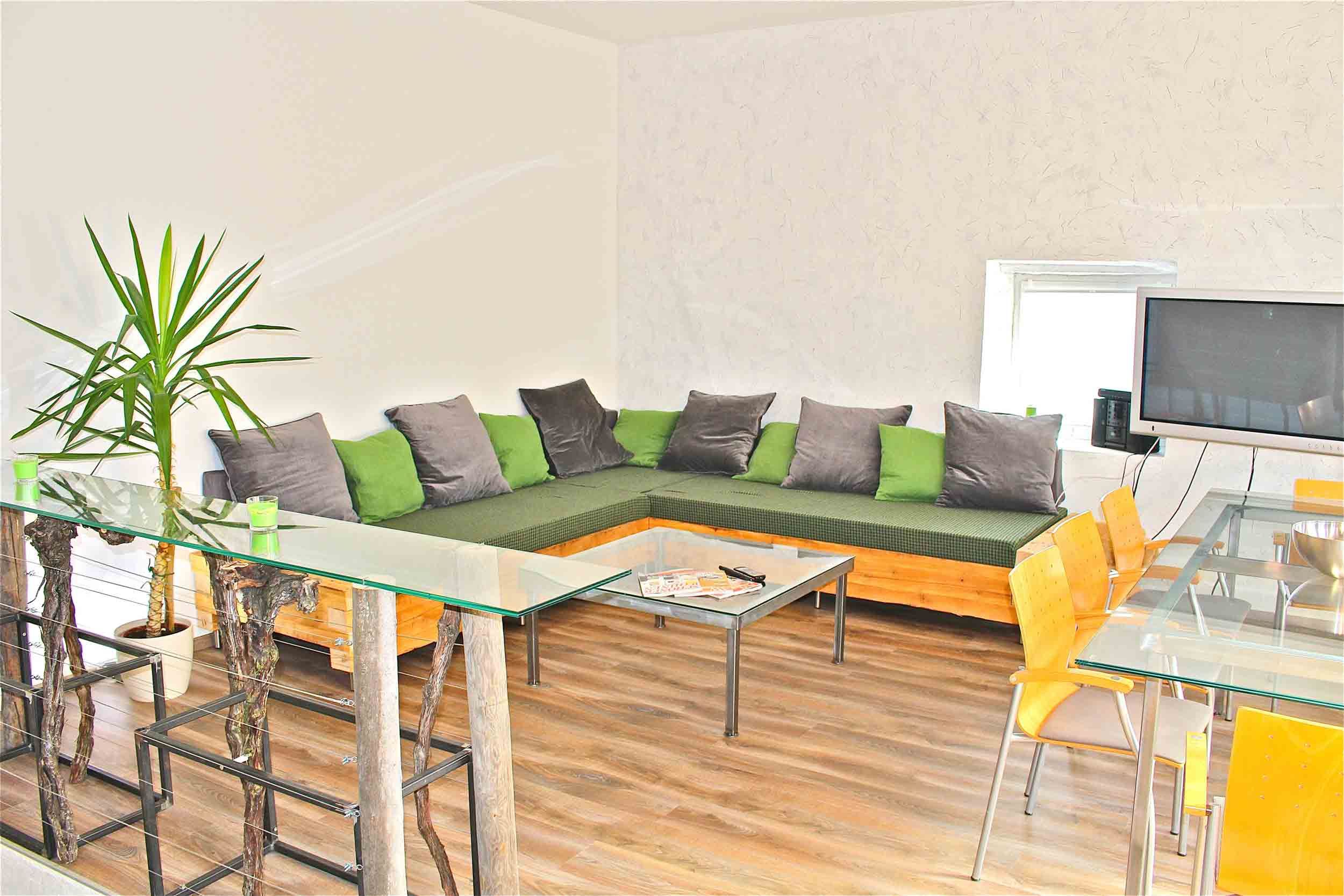 Modern living room with corner sofa, glass table and TV.