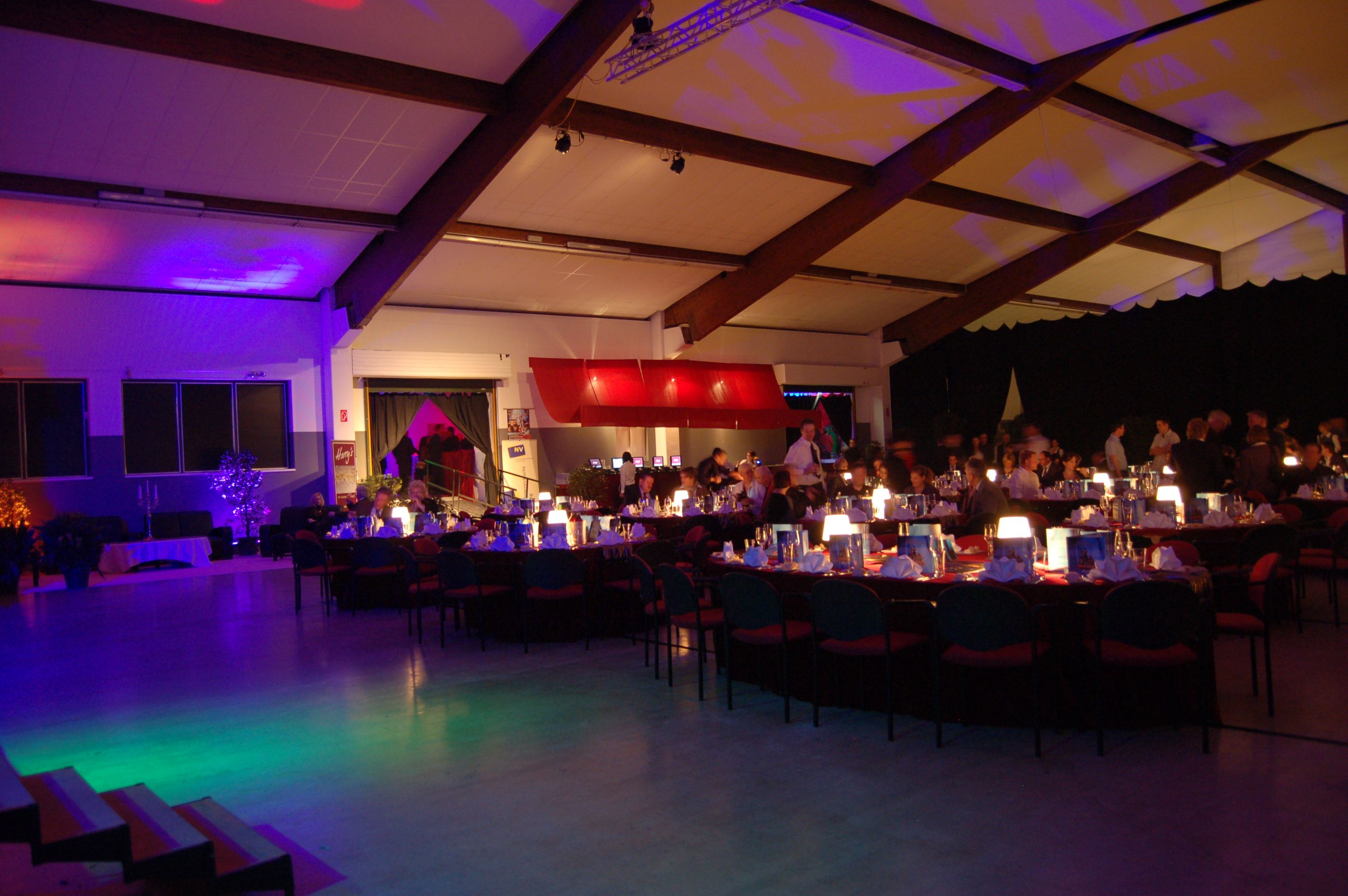 Interior view of a festively lit hall with laid tables and guests.