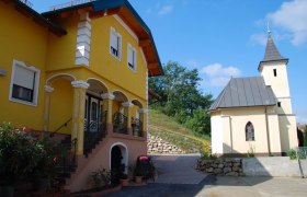 Yellow building with stairs and a small church next to it.