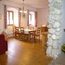 Cozy dining area with wooden table and chairs, red curtains and stone wall.