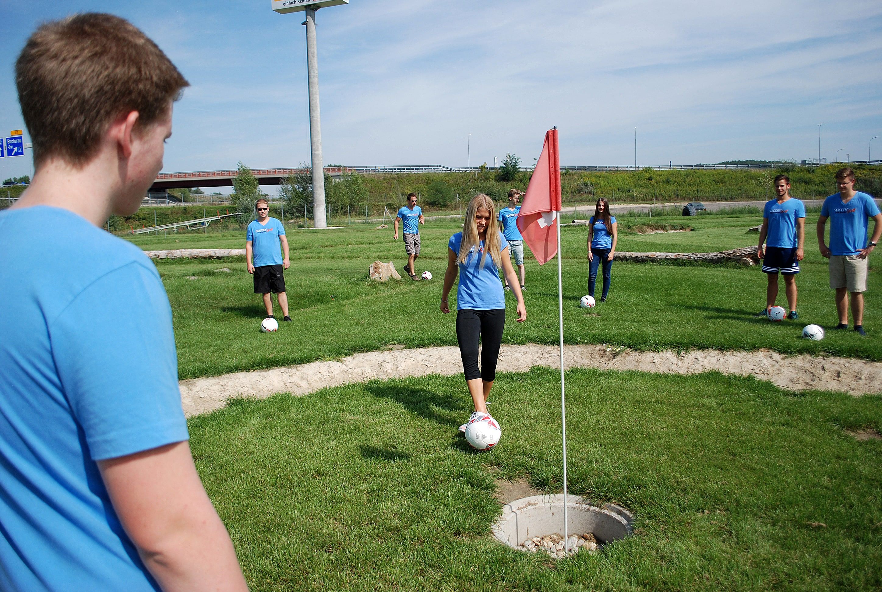 A group of young people playing soccer golf.