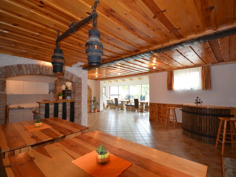 Interior view of a rustic dining room with wooden tables and ceilings, bar area and large windows.