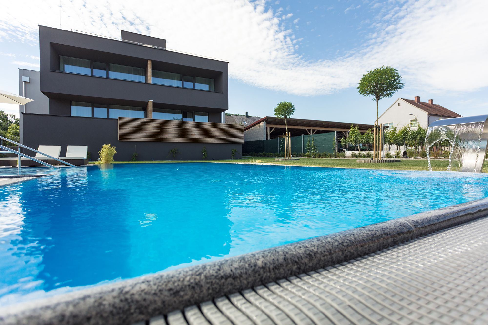 Modern building with pool in the foreground and blue sky in the background.