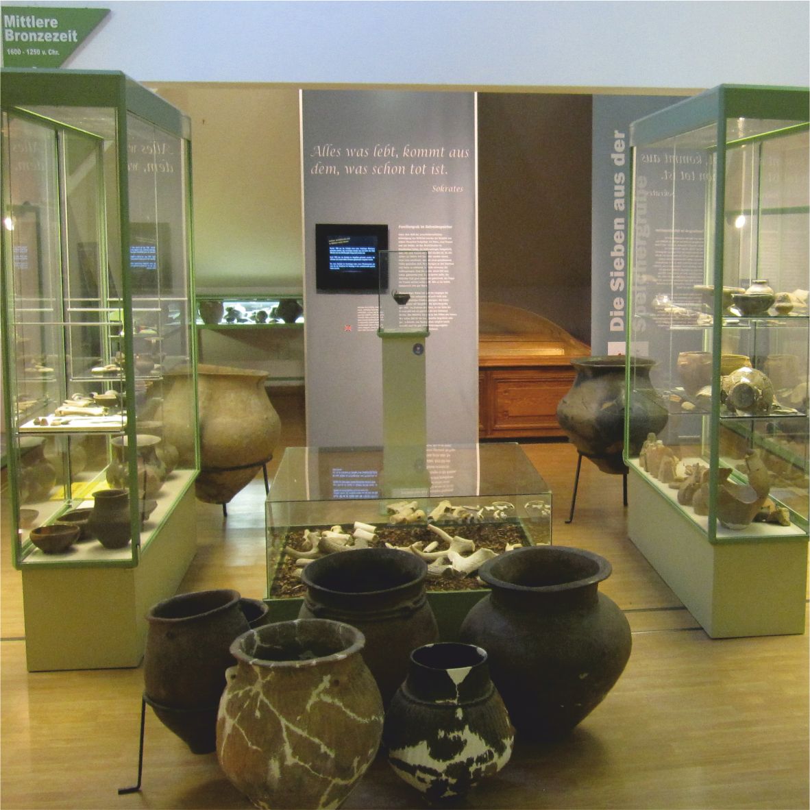 Museum exhibition with antique clay vessels and display cases.