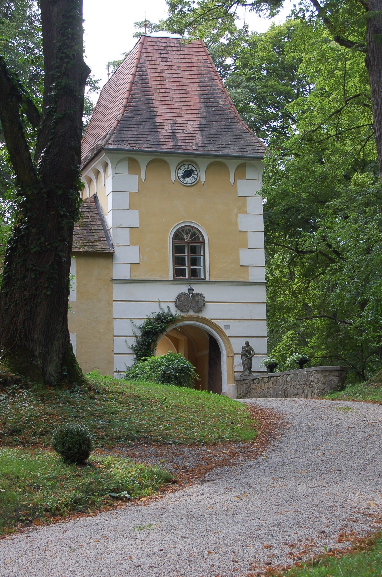 Historic building with tower and clock in a wooded area.