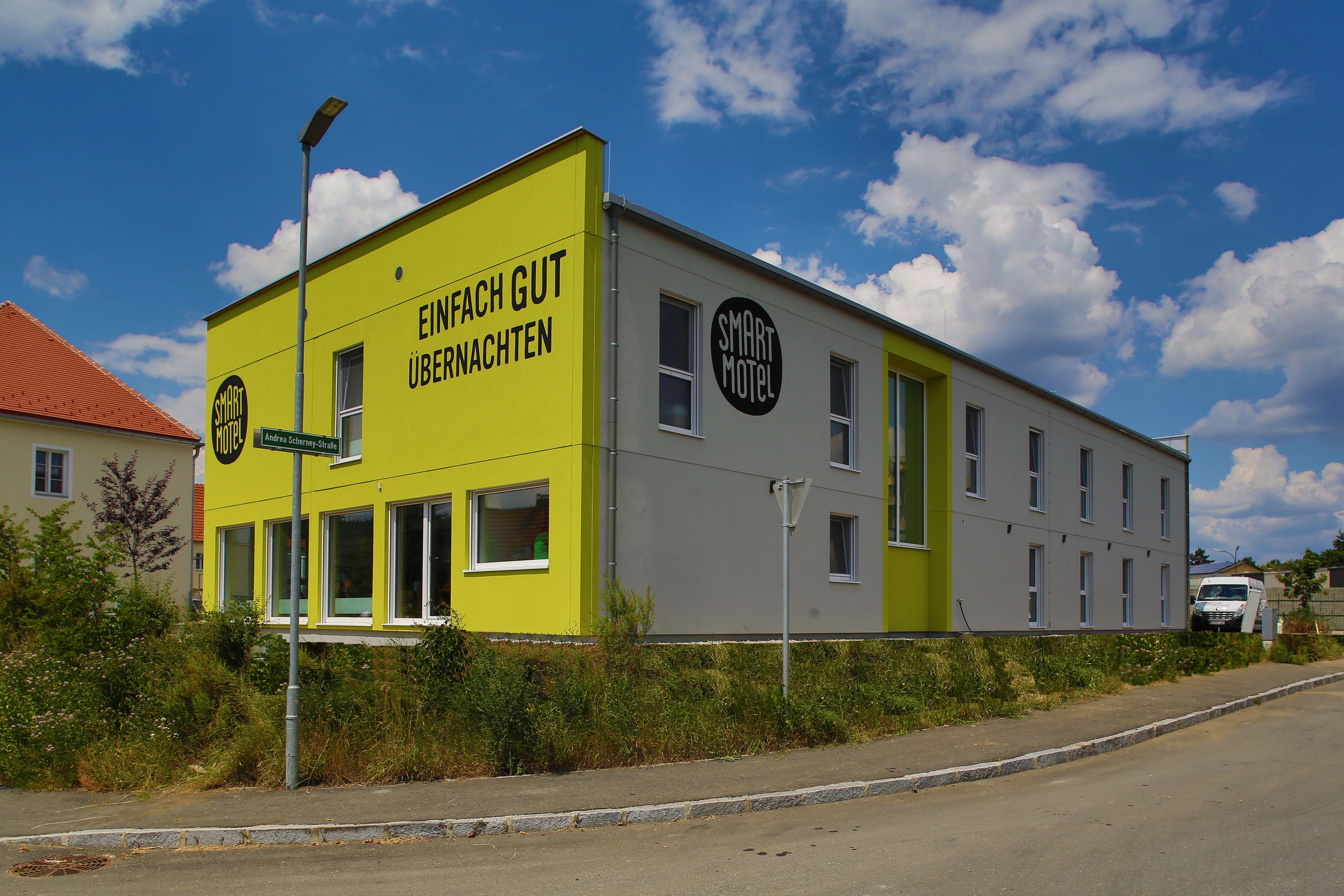Exterior view of a modern, two-storey motel with a yellow façade and the inscription 'Einfach gut übernachten'.