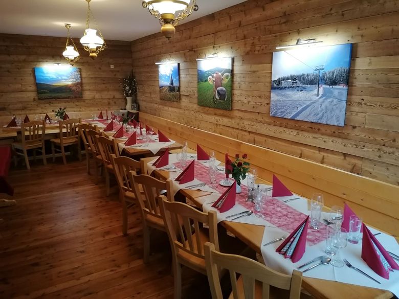 A festively decorated hall with wooden walls, decorated with pictures and red napkins on the tables.