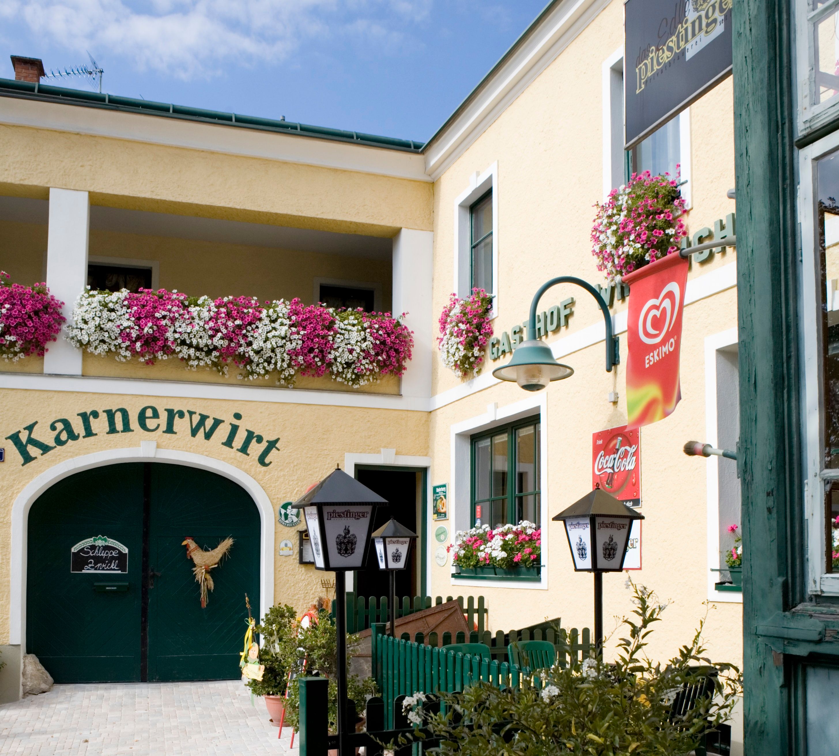 Entrance to an inn with flowers and advertising signs.