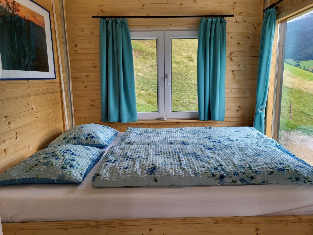Wooden interior with bed, window and blue curtains.